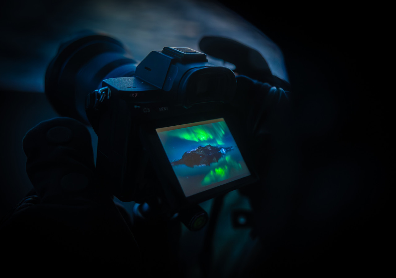 Viewing the northern lights on the back of a camera in Scoresbysund Secret Atlas