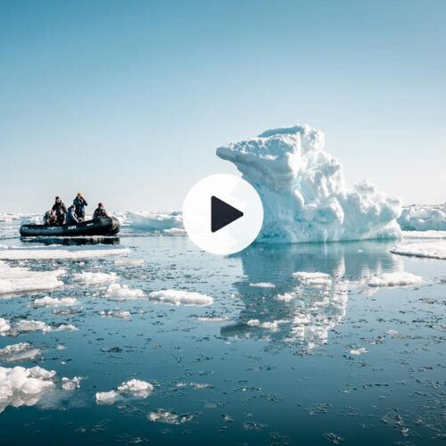 Zodiac cruise between icebergs in Svalbard with play button